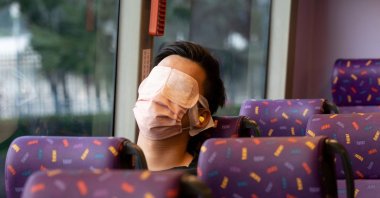 A passenger sleeps on a bus operated by a Hong Kong travel agency offering a five-hour "quiet bus" tour marketed as a "route to nowhere" for travel-craving and restless residents to snooze on board in Hong Kong, Nov. 14, 2021. (AFP Photo)