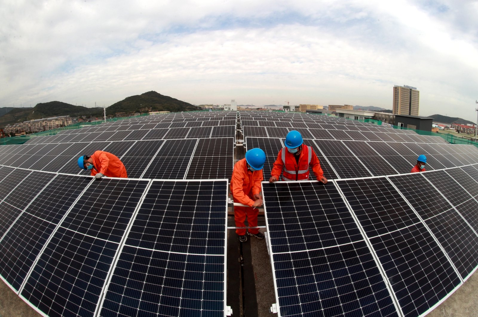 Workers install photovoltaic panels on the roof of a fish processing plant in Zhoushan, Zhejiang province, China, Nov. 16, 2021. (Photo by Getty Images)