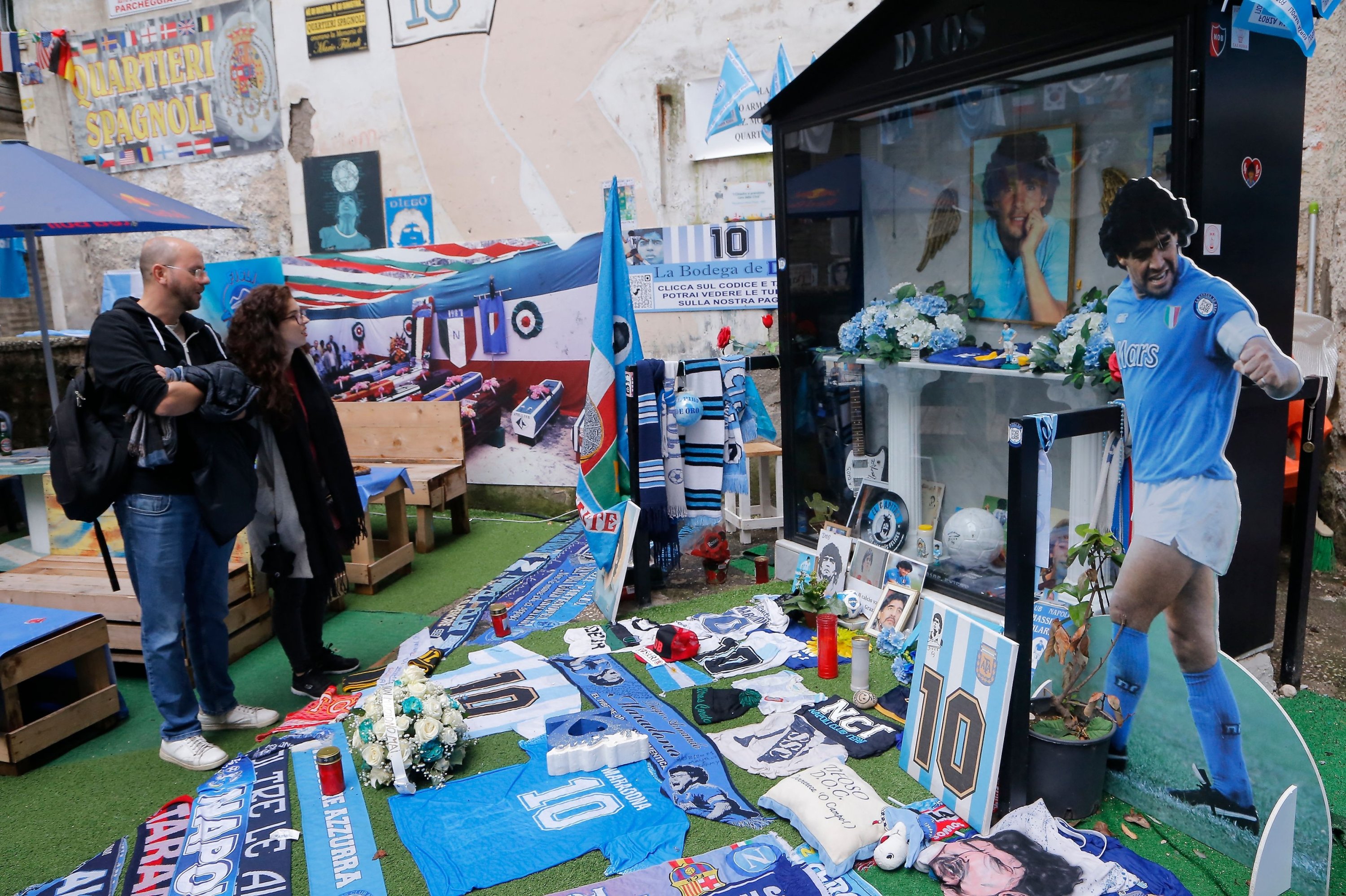 Tourists stand by a makeshift shrine in homage to late Argentinian football legend Diego Maradona in the Spanish Quarters, Naples, Italy, Nov. 23, 2021. (AFP Photo)