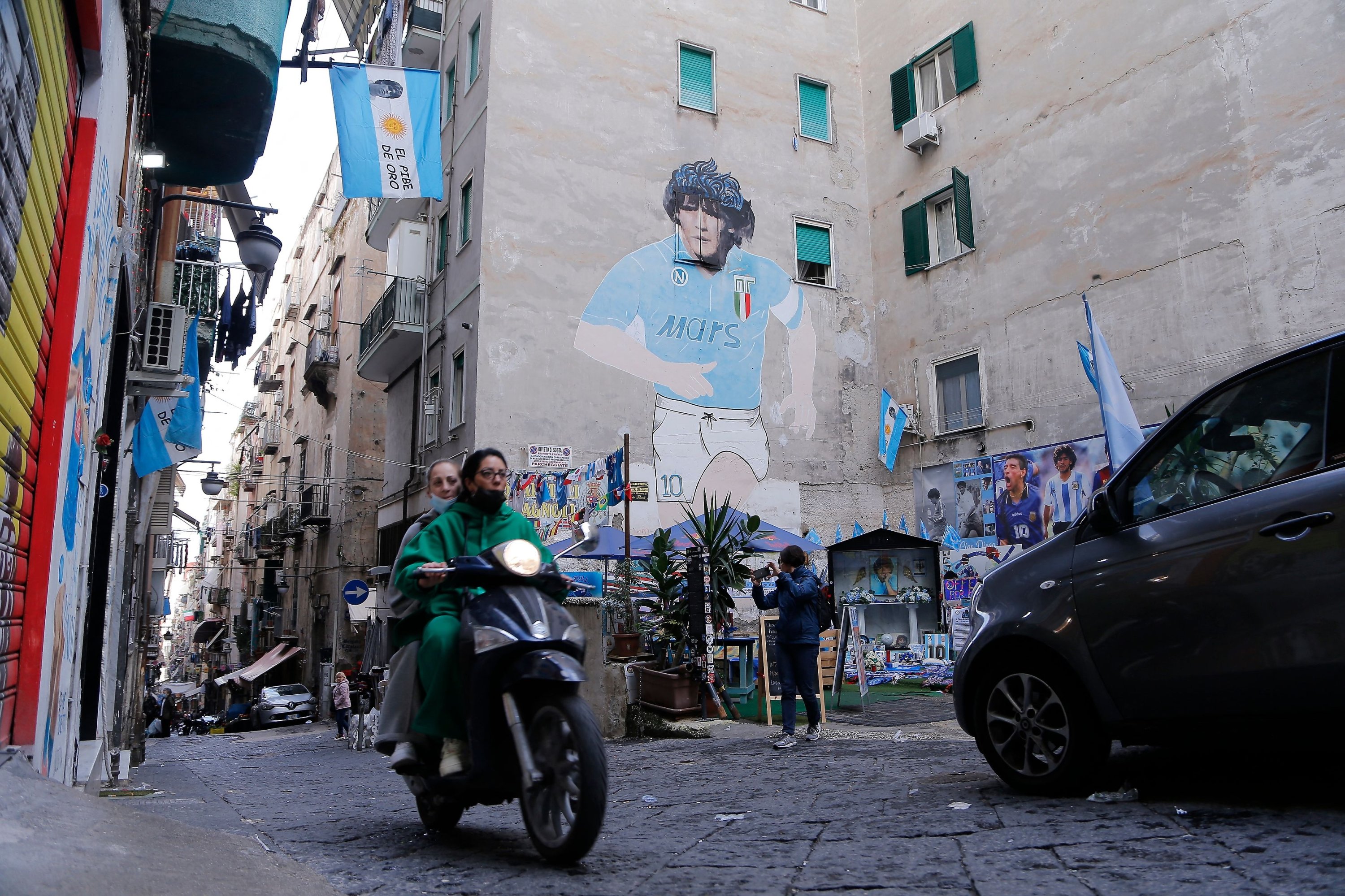 A scooter drives past a mural painting of late Argentinian football legend Diego Maradona in the Spanish Quarters, Naples, Italy, Nov. 23, 2021. (AFP Photo)