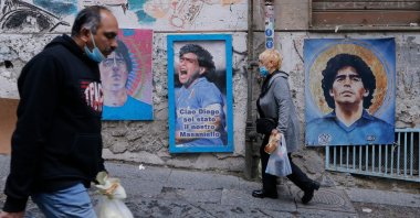 Residents walk past pictures of late Argentinian football legend Diego Maradona across the so-called "Maradona square" in the Spanish Quarters, Naples, Italy, Nov. 23, 2021. (AFP Photo)