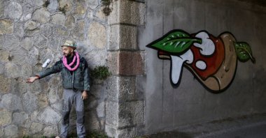Italian street artist Pier Paolo Spinazze, 39, known as "Cibo" (Italian for food), uses spray paint to cover racist graffiti with a mural of pizza, near Verona, Italy, Nov. 18, 2021. (Reuters Photo)