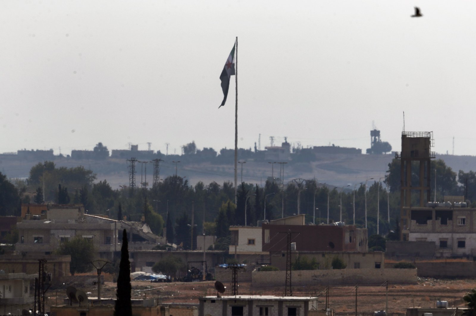 Photo taken from the Turkish side of the border between Turkey and Syria, in Akçakale, Şanlıurfa province, southeastern Turkey, shows the Syrian opposition flag flying on a pole in Tal Abyad, Syria, Oct. 22, 2019. (AP File Photo)