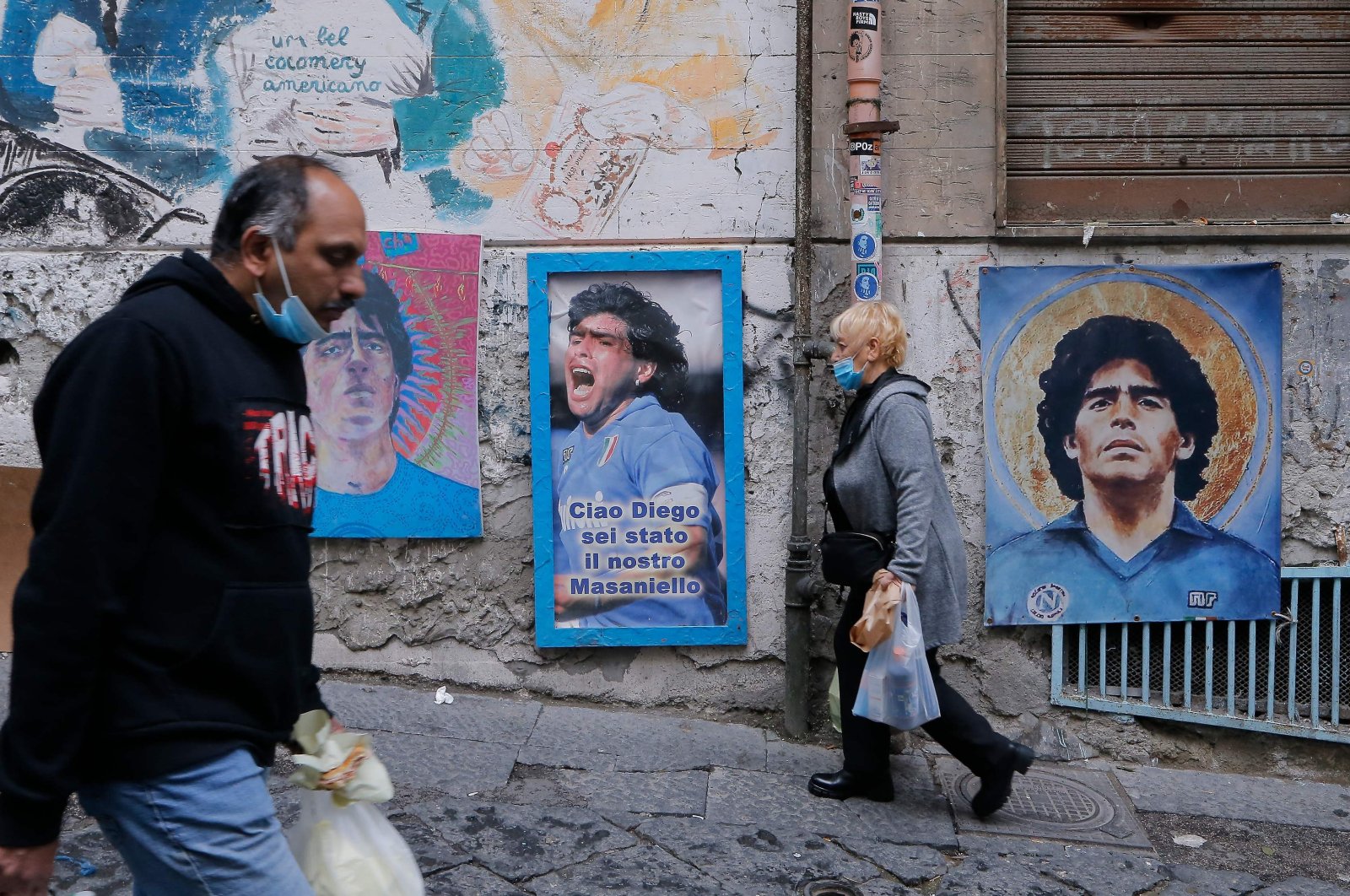 Residents walk past pictures of late Argentinian football legend Diego Maradona across the so-called &quot;Maradona square&quot; in the Spanish Quarters, Naples, Italy, Nov. 23, 2021. (AFP Photo)