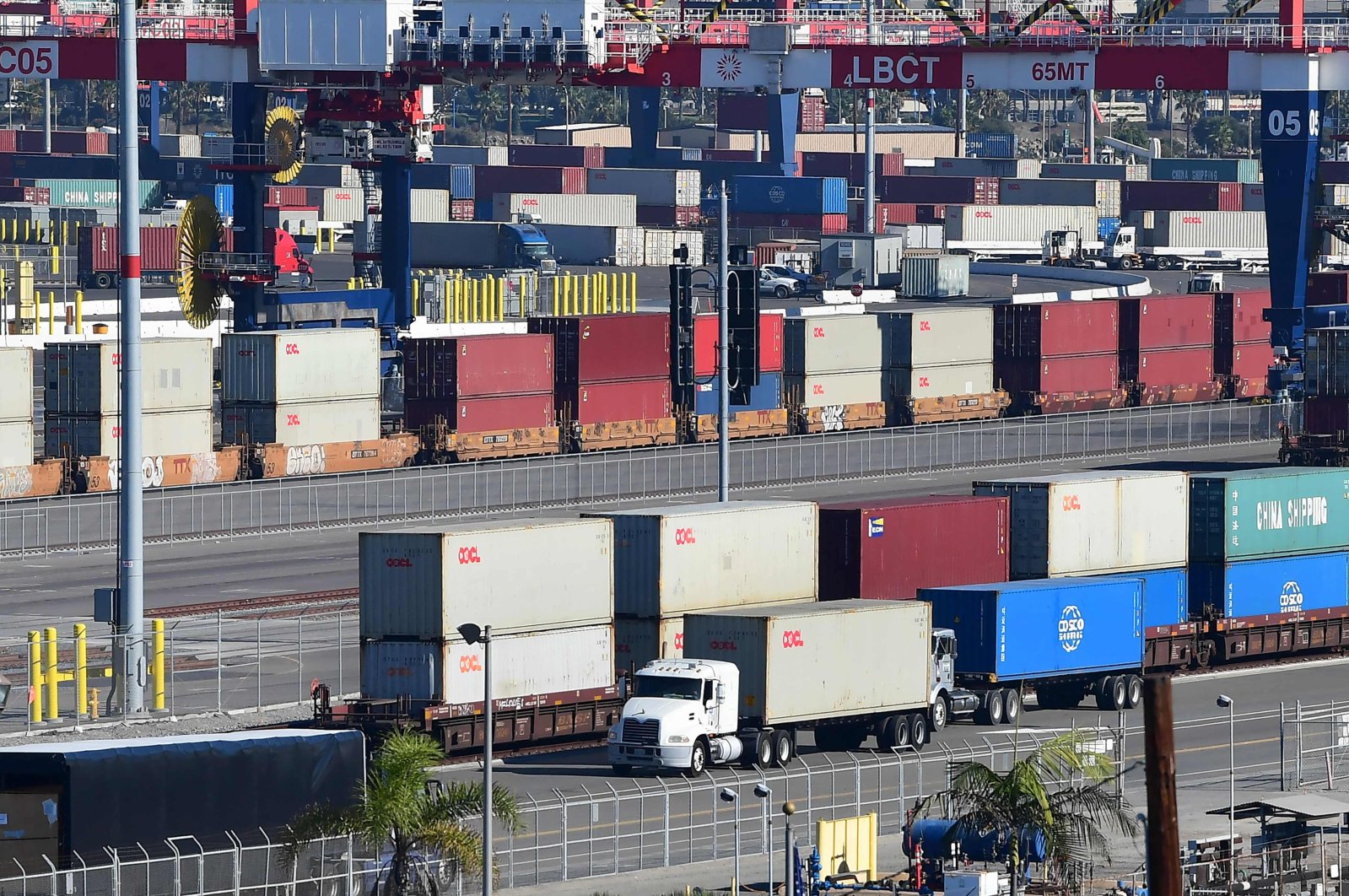 A container truck makes its way past a row of containers stacked at the Port of Long Beach, California, U.S., Nov. 12, 2021. (AFP Photo)