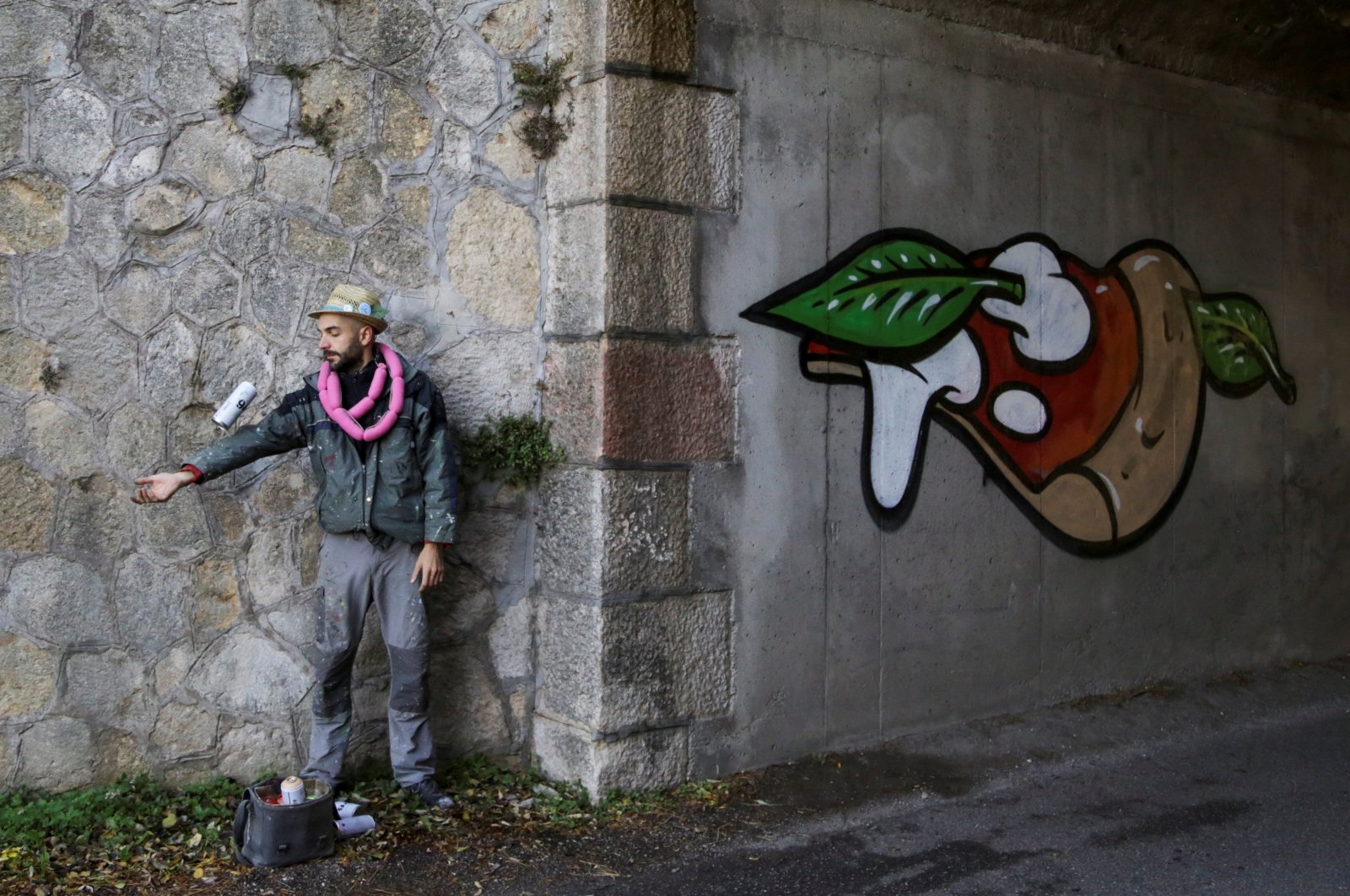 Italian street artist Pier Paolo Spinazze, 39, known as &quot;Cibo&quot; (Italian for food), uses spray paint to cover racist graffiti with a mural of pizza, near Verona, Italy, Nov. 18, 2021. (Reuters Photo)