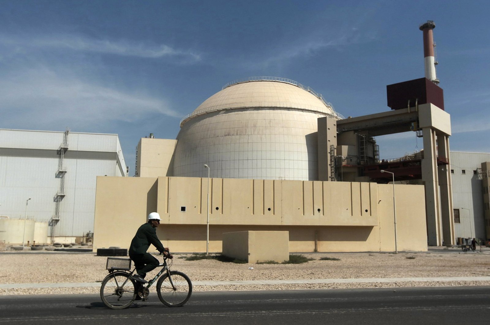A worker rides a bicycle in front of the nuclear reactor at the Bushehr nuclear power plant, Iran, Oct. 26, 2010. (AP Photo)