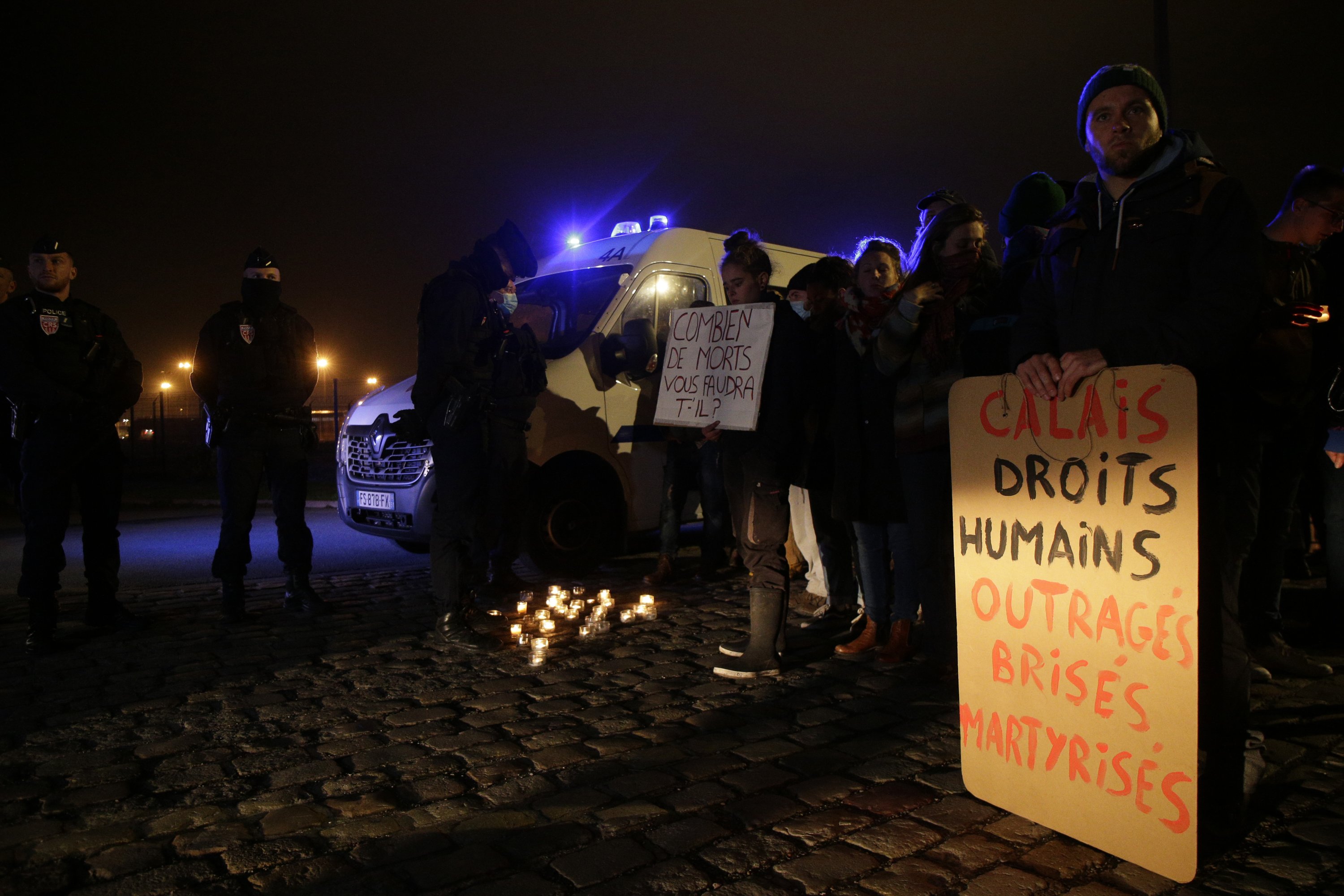 Activists and members of associations defending migrants' rights gather with posters reading "Human rights, outraged, smashed, martyrized" outside the port of Calais, northern France, Nov. 24, 2021. (AP Photo)