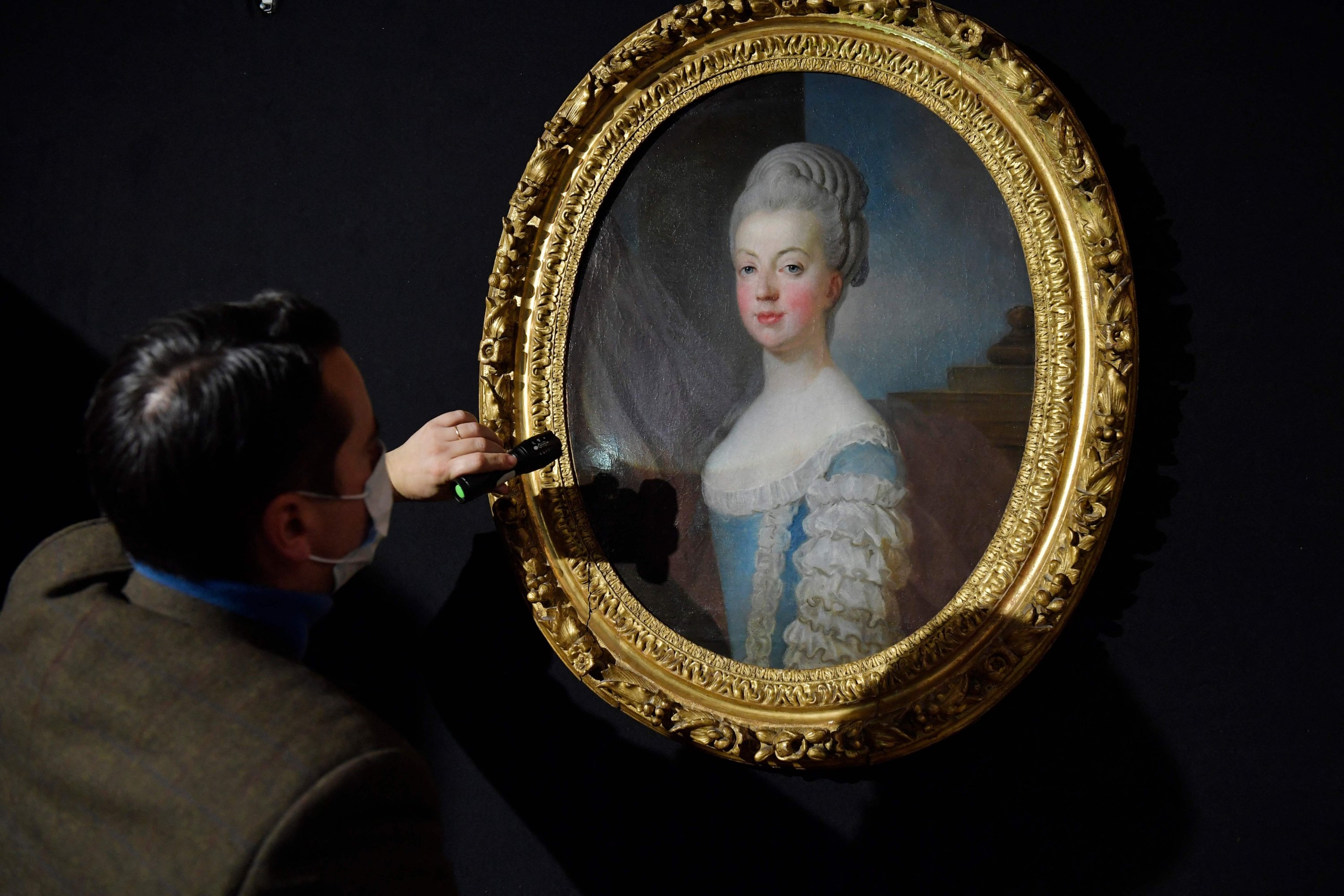 A man examines a painting by Joseph Siffried Duplessis & Atelier Carpentras, before its auction at Auguttes auction house in Neuilly sur Seine near Paris, France, Nov. 23, 2021. (AFP Photo)