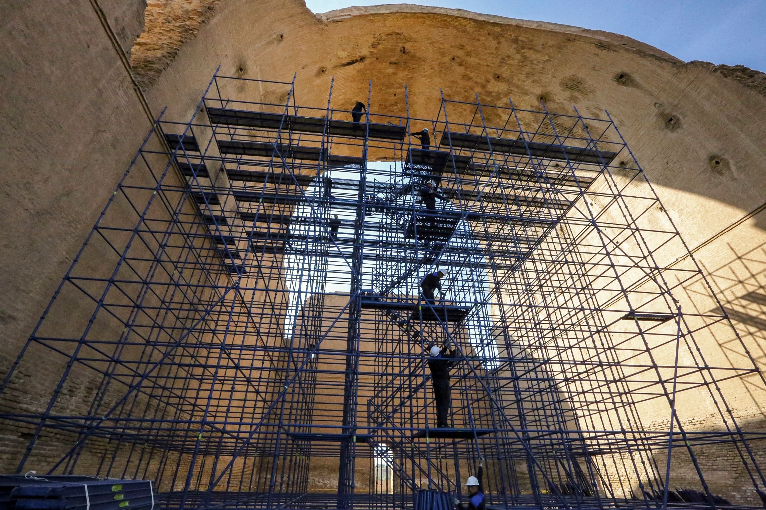 Pekerja konservasi berdiri di sepanjang perancah di Arch of Ctesiphon, juga dikenal sebagai Taq Kisra (Khosrow's Arch), di situs kuno Ctesiphon dekat al-Madain, Irak tengah, 24 November 2021. (AFP Photo)