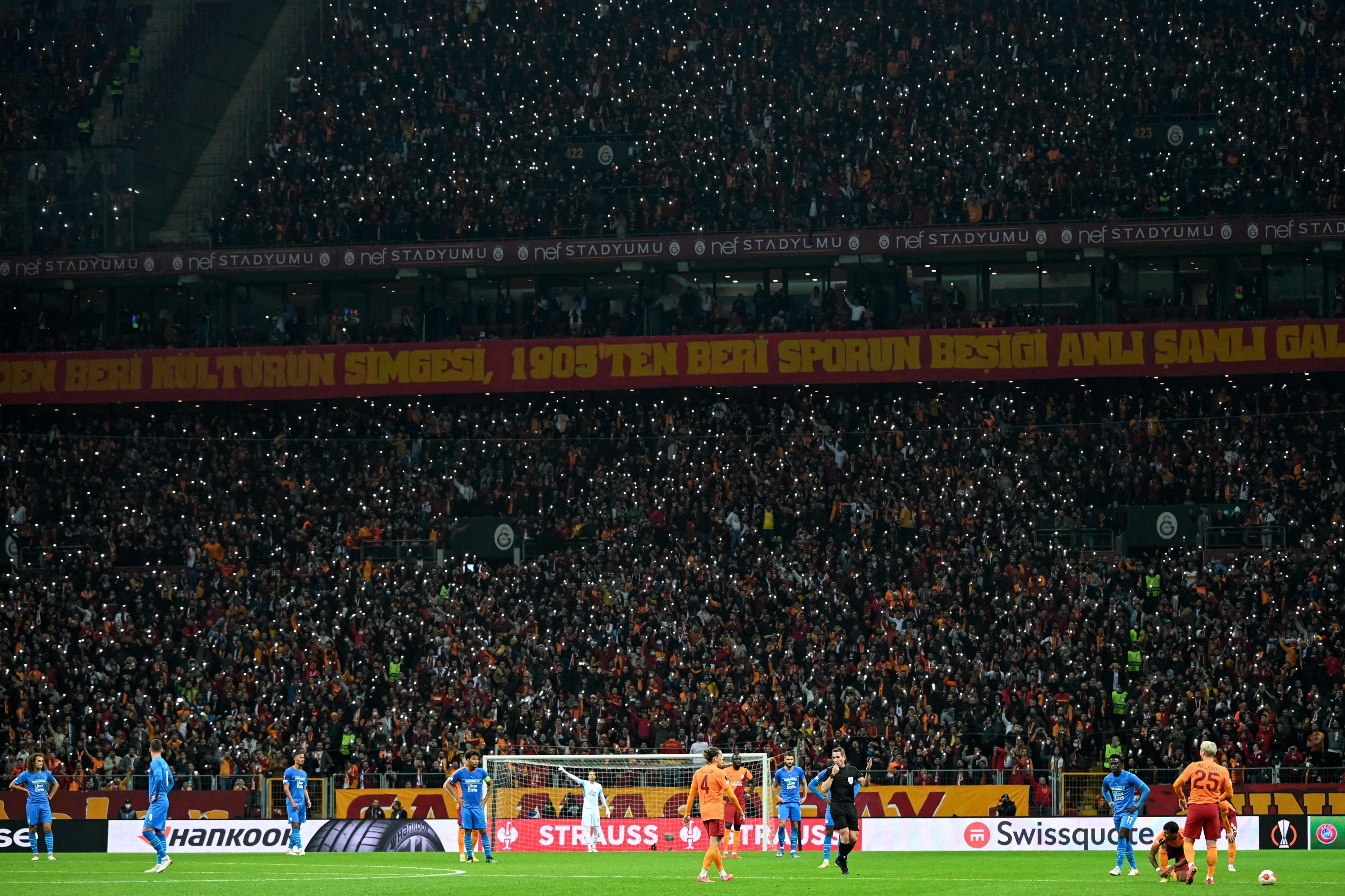 Pendukung menggunakan senter ponsel selama pertandingan sepak bola Liga Eropa UEFA antara Galatasaray dan Olympique de Marseille di Stadion Nef, di Istanbul, pada 25 November 2021. (AFP Photo)