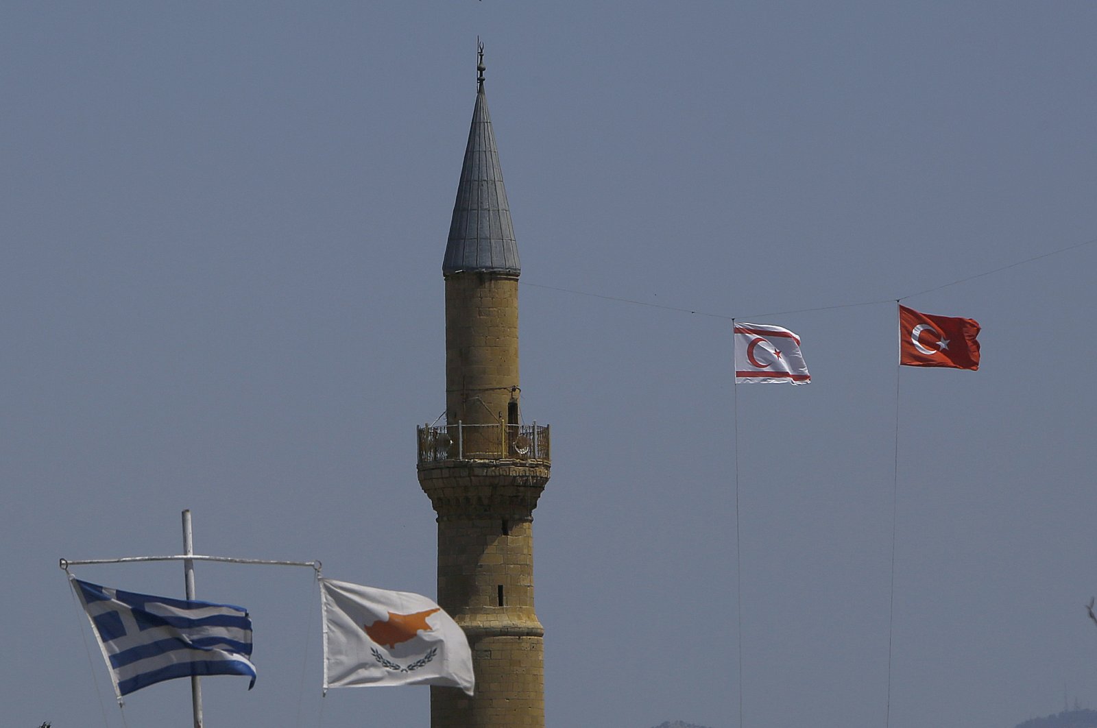 The flags of Turkey and the TRNC flutter by the minaret of the Hagia Sofia with the flags of Greece and Greek Cyprus on poles below, in the divided capital Lefkoşa, TRNC, April 26, 2021. (AP File Photo)