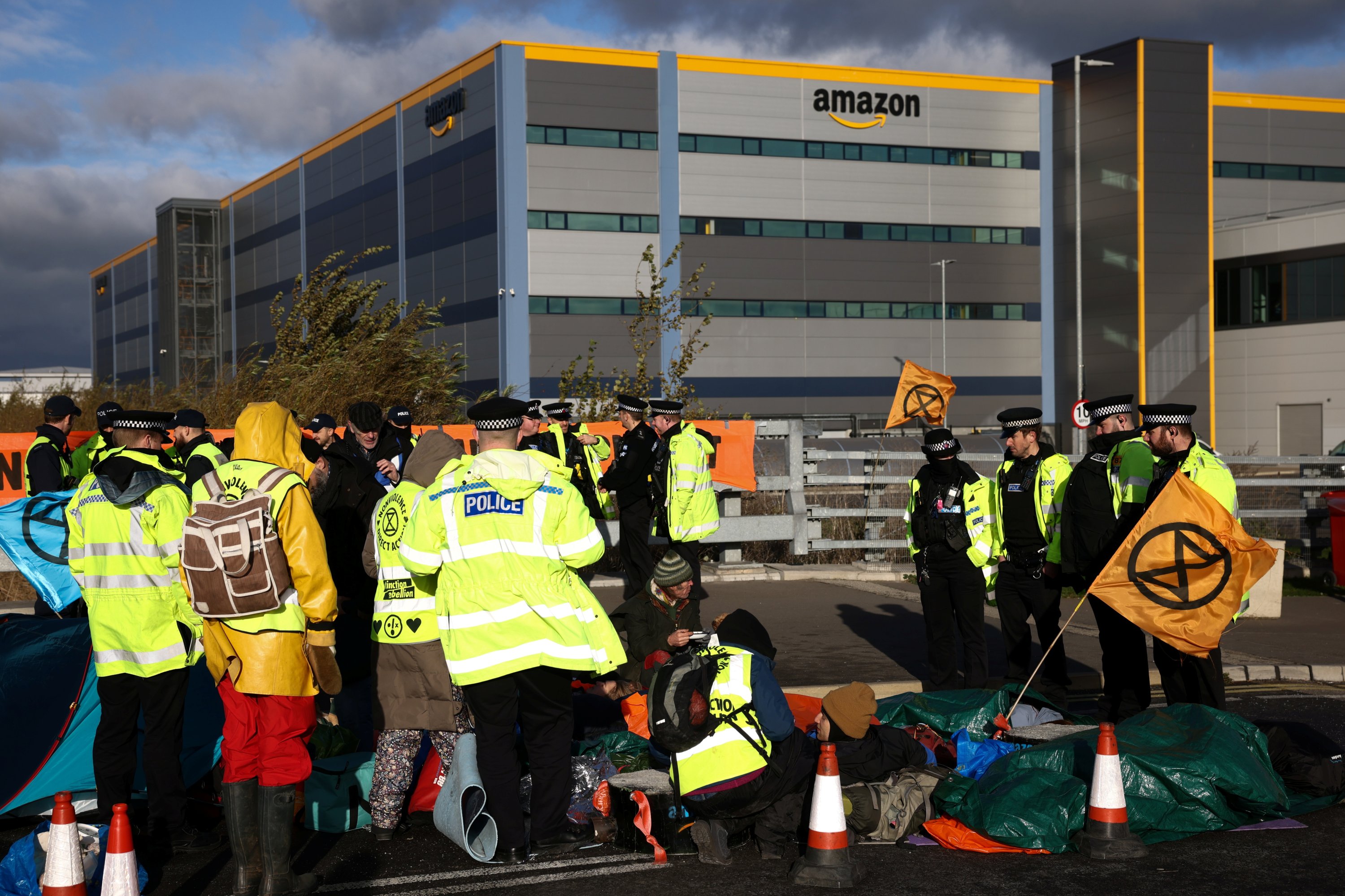 Police officers speak with protesters, as Extinction Rebellion activists block a street outside an Amazon fulfilment centre in Tilbury, Essex, Britain, Nov. 26, 2021. (Reuters Photo)