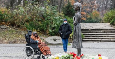An elderly woman pays her tributes near the statue dedicated to the victims of the Holodomor who died of starvation in 1932-33, Kyiv, Ukraine, Nov. 26, 2020. (Shutterstock Photo)