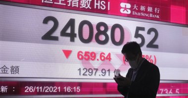 A man walks past a bank's electronic board showing the Hong Kong share index in Hong Kong, Nov. 26, 2021. (AP Photo)
