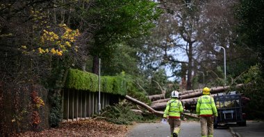 Firefighters arrive to inspect the damage as residents clear branches from a fallen tree in Birkenhead, England, Nov. 27, 2021. (AFP Photo)