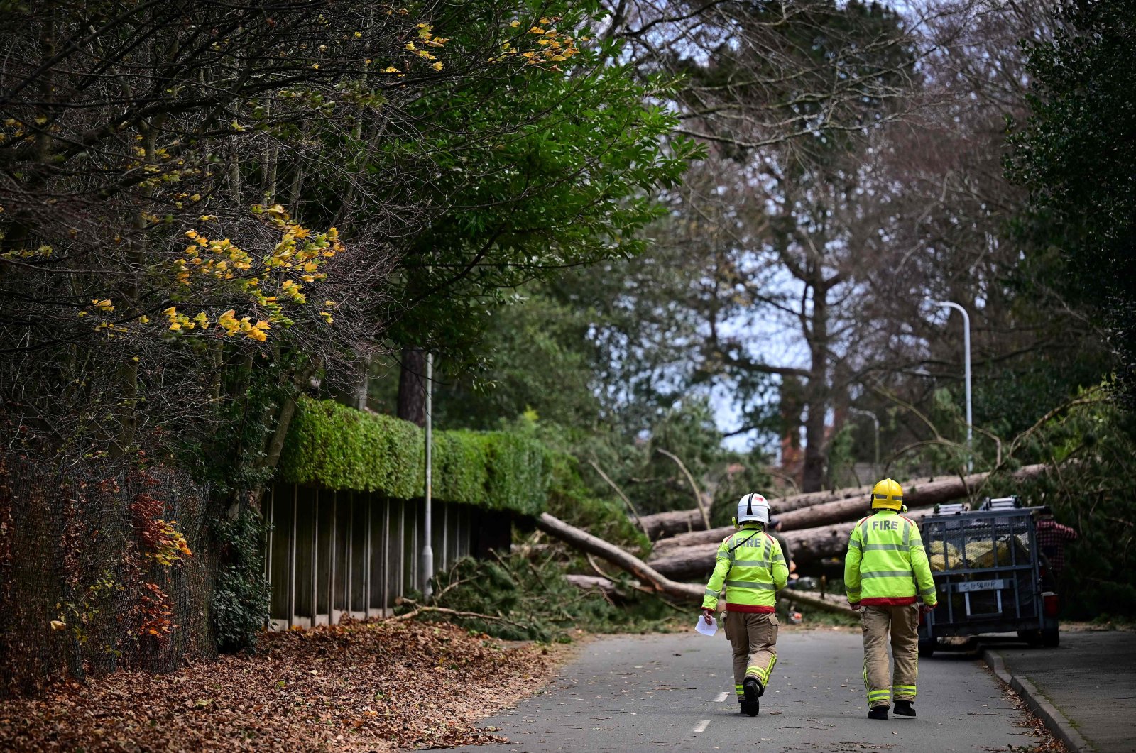 Firefighters arrive to inspect the damage as residents clear branches from a fallen tree in Birkenhead, England, Nov. 27, 2021. (AFP Photo)
