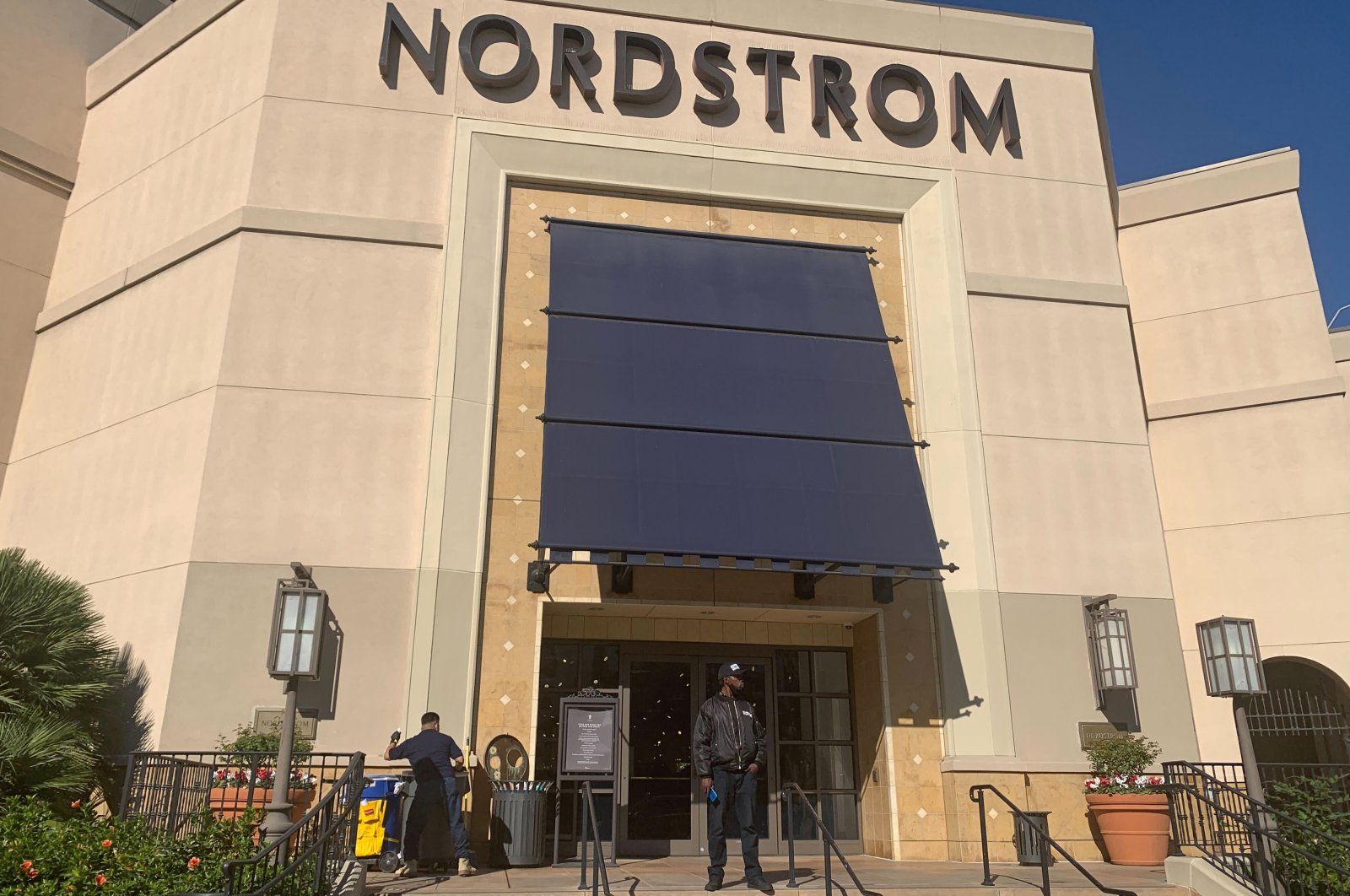 A security guard stands outside the Nordstrom store at The Grove retail and entertainment complex in Los Angeles, Tuesday, Nov. 23, 2021. (AP Photo)