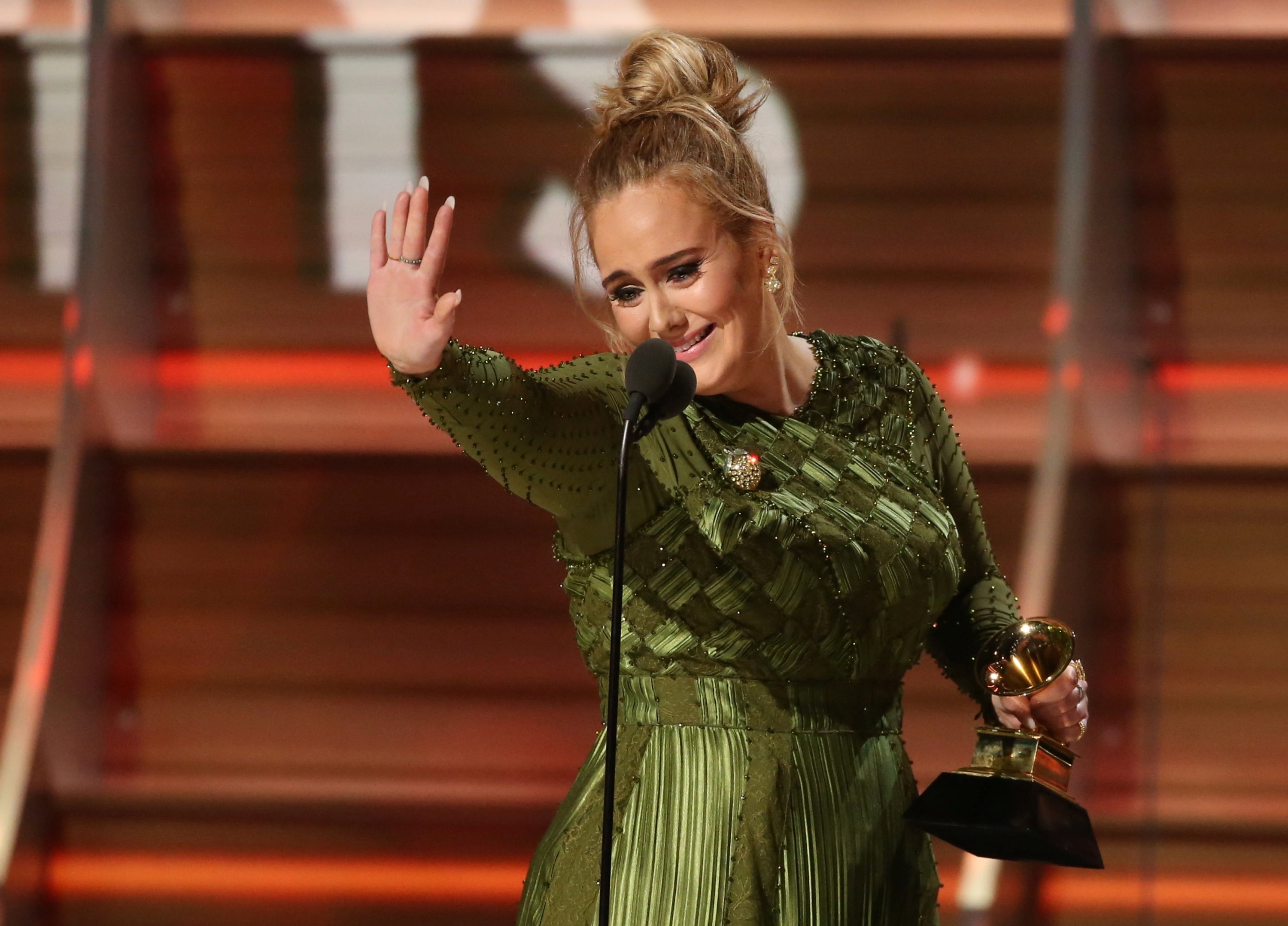 Adele waves to singer Beyonce who is in the audience as she and co-songwriter Greg Kurstin (not pictured) accept the Grammy for Song of the Year for 