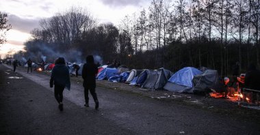 Migrants walk next to their tents in Grande-Synthe near Dunkirk, France, Nov. 25, 2021. (EPA Photo)