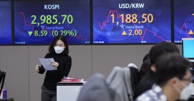 A currency trader passes by screens showing the Korea Composite Stock Price Index (KOSPI) and the foreign exchange rate between U.S. dollar and South Korean won (R) at the foreign exchange dealing room of the KEB Hana Bank headquarters in Seoul, South Korea, Thursday, Nov. 25, 2021. (AP Photo)