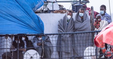 Braving the cold, exhausted migrants await disembarkation operations from the Alan Kurdi ship at the port of Olbia, Italy. (Getty Images)