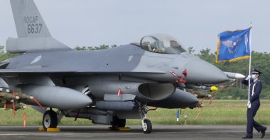A Taiwanese Air Force flag bearer passes by one of the newly commissioned upgraded F-16V fighter jets at Air Force base in Chiayi in southwestern Taiwan, Nov. 18, 2021. (AP Photo)