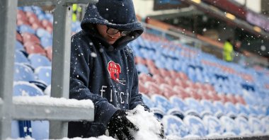 A boy gathers snow from a pitchside railing ahead of the English Premier League football match between Burnley and Tottenham Hotspur at Turf Moor in Burnley, U.K., Nov. 28, 2021. (AFP Photo)