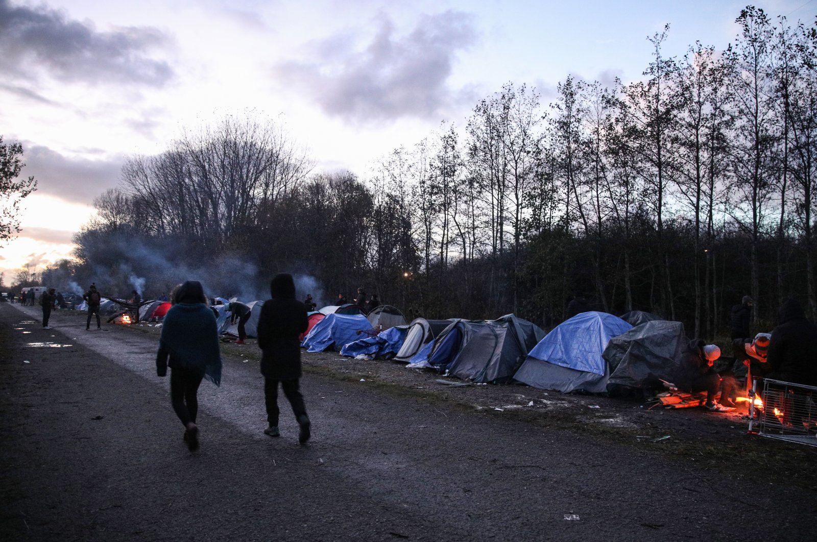 Migrants walk next to their tents in Grande-Synthe near Dunkirk, France, Nov. 25, 2021. (EPA Photo)