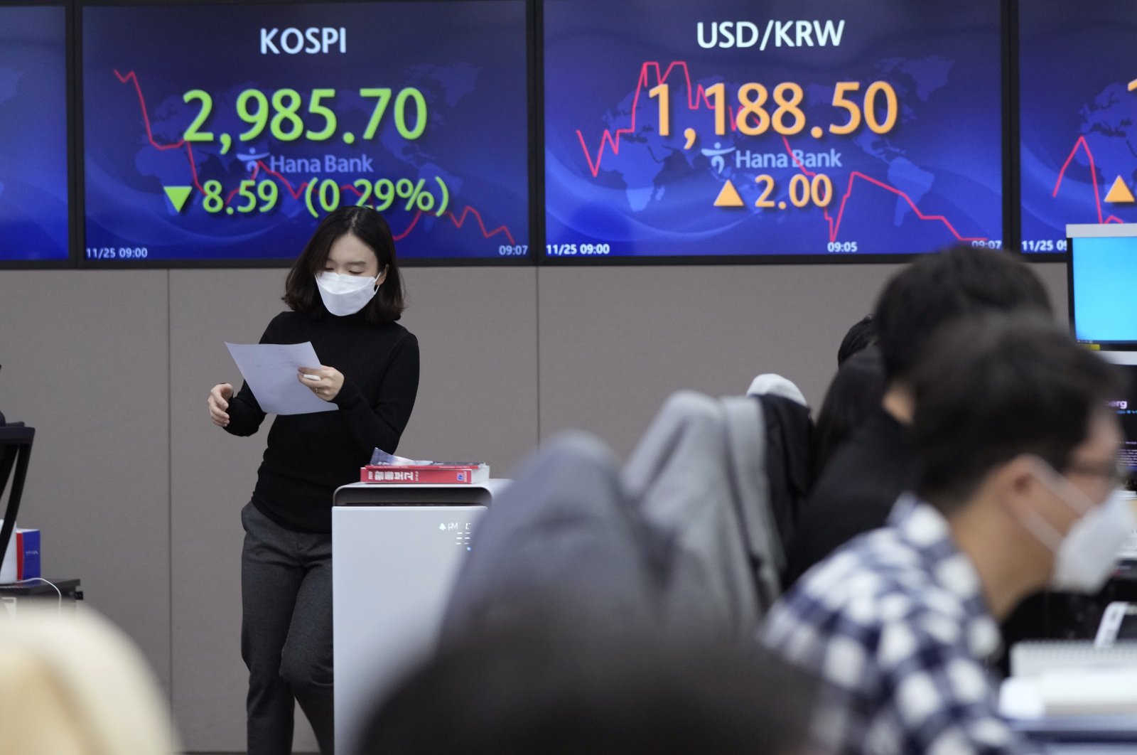 A currency trader passes by screens showing the Korea Composite Stock Price Index (KOSPI) and the foreign exchange rate between U.S. dollar and South Korean won (R) at the foreign exchange dealing room of the KEB Hana Bank headquarters in Seoul, South Korea, Thursday, Nov. 25, 2021. (AP Photo)
