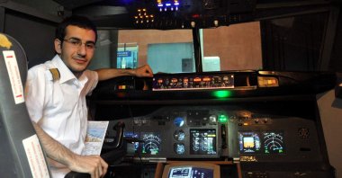 Aviation-lover Alihan Kolaylı seen in front of the Boeing 737-800 airplane cockpit he created in his basement 10 years ago, in Trabzon, Turkey, Nov. 29, 2021. (IHA Photo)