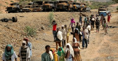 Villagers return from a market to Yechila town in south central Tigray walking past scores of burned vehicles, in Tigray, Ethiopia, July 10, 2021. (Reuters Photo)