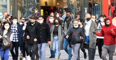 Pedestrians wearing protective masks against COVID-19 walk on a street, in the capital Ankara, Turkey, Nov. 28,  2021. (AFP PHOTO)