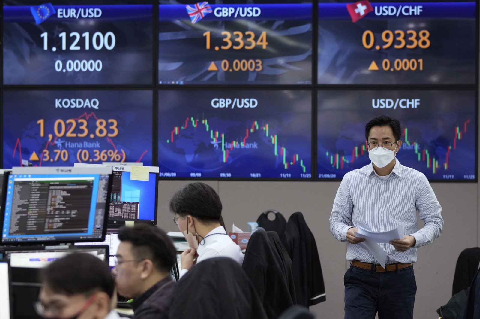 A currency trader walks by the screens showing the foreign exchange rates at the foreign exchange dealing room of the KEB Hana Bank headquarters in Seoul, South Korea, Nov. 25, 2021. (AP Photo)