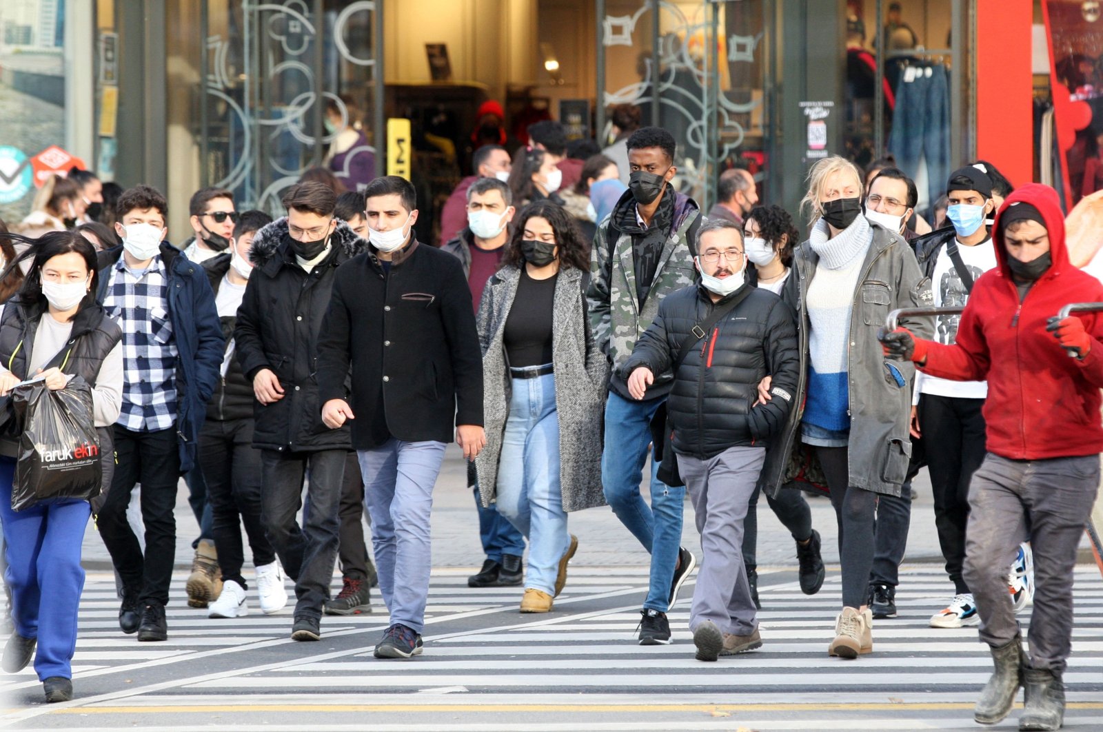Pedestrians wearing protective masks against COVID-19 walk on a street, in the capital Ankara, Turkey, Nov. 28,  2021. (AFP PHOTO)
