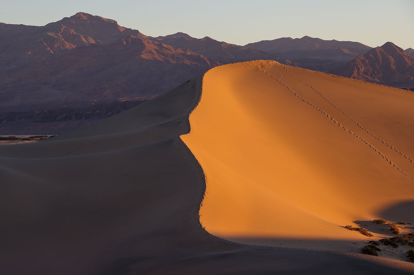 Bukit pasir bergulir memukau dengan matahari terbit di atas Death Valley