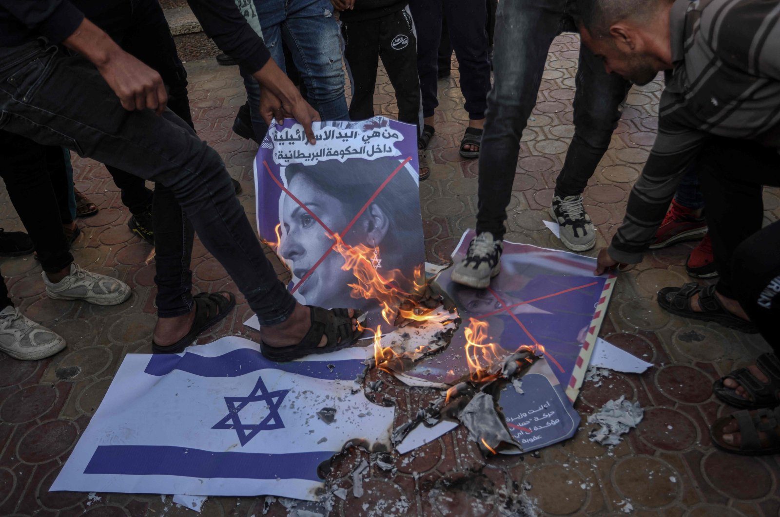 Palestinians burn Israel&#039;s flag and posters depicting the crossed-out face of Home Secretary Priti Patel, during a rally for Palestinian factions against Britain&#039;s designation of Hamas as a terrorist group, Rafah, southern Gaza Strip, Nov. 23, 2021. (AFP Photo)