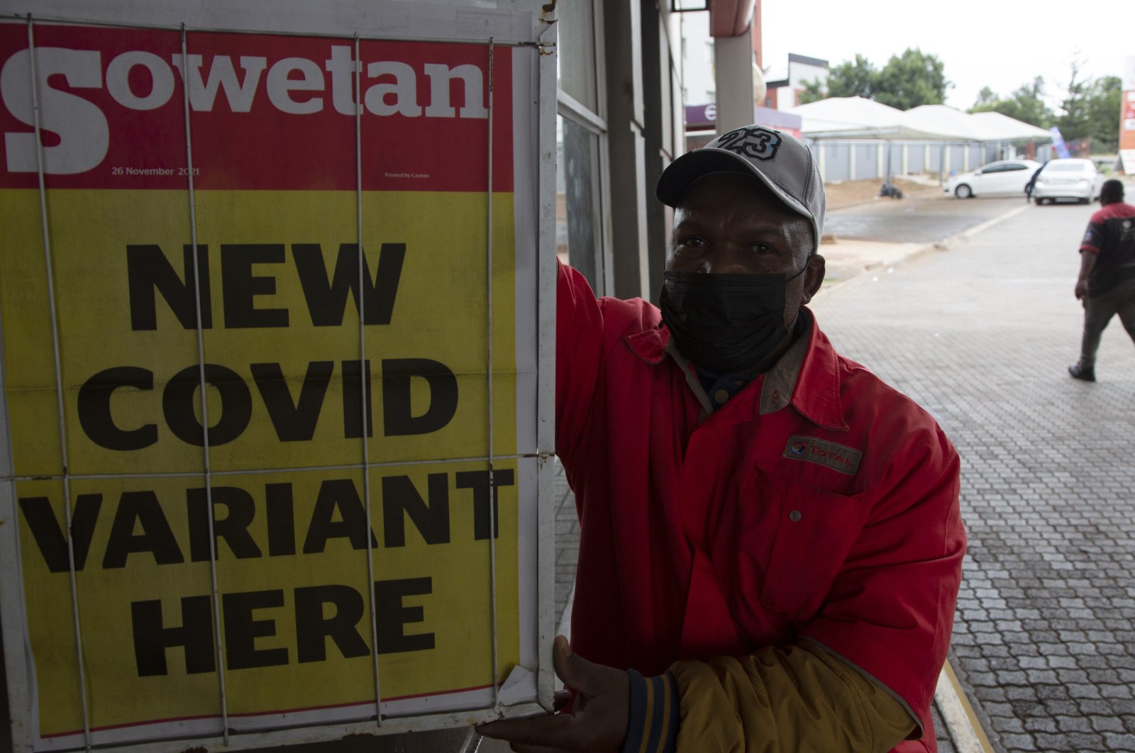 A petrol attendant stands next to a newspaper headline after the omicron variant was reported in the country, in Pretoria, South Africa, Saturday, Nov. 27, 2021. (AP Photo)