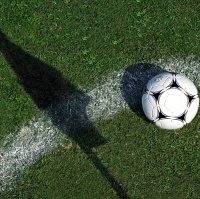 A football is seen as the corner flag casts a shadow on the pitch. (Getty Images) 