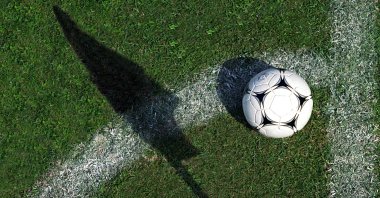 A football is seen as the corner flag casts a shadow on the pitch. (Getty Images) 