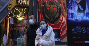 Residents wearing masks as protection against the coronavirus walk past shop decorations in Beijing, China, Nov. 30, 2021. (AP Photo)
