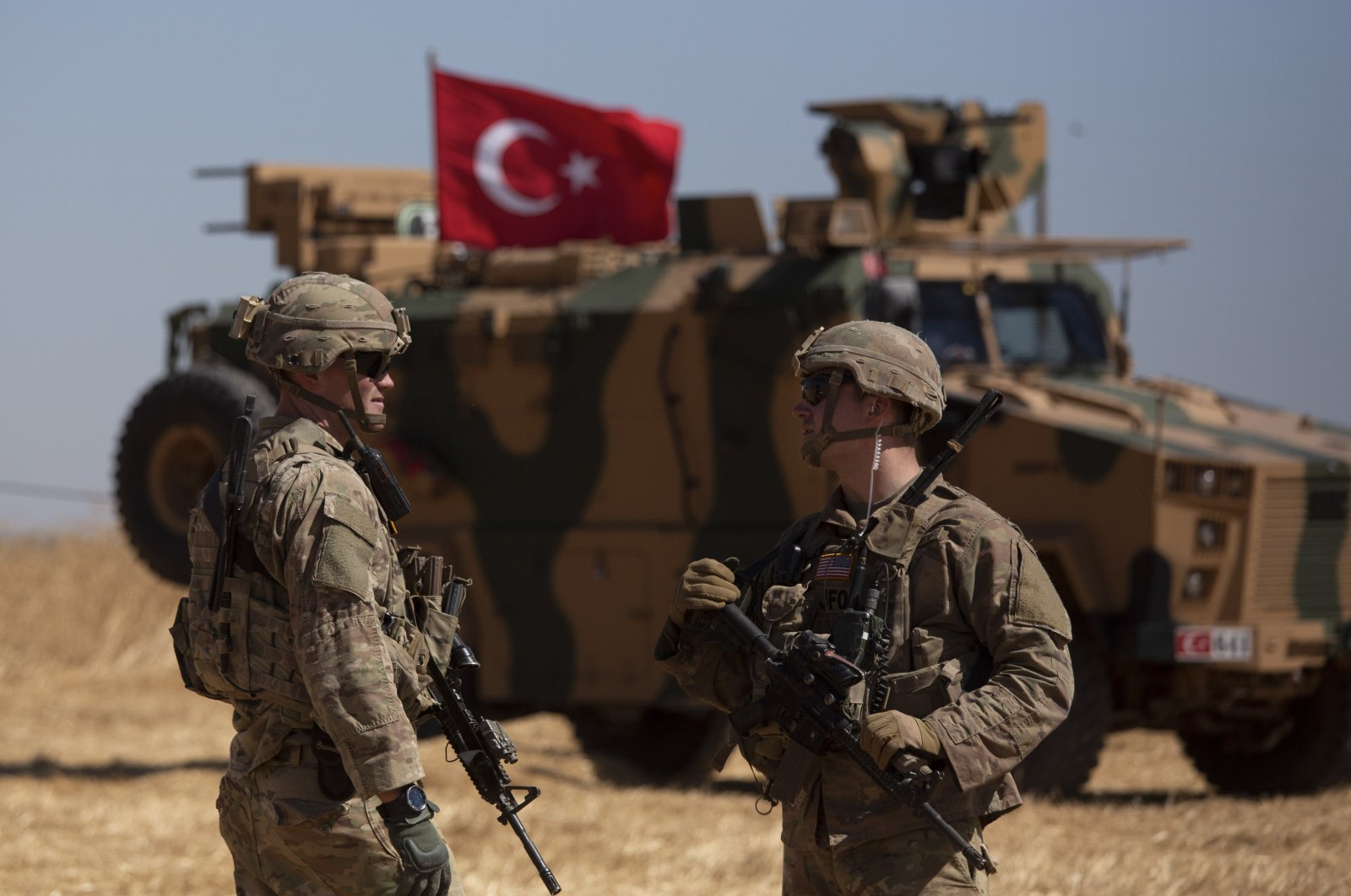 Soldiers stand near a Turkish armored vehicle during the first American-Turkish joint patrol in the so-called "safe zone" on the Syrian side of the border with Turkey near Tal Abyad, Syria, Sept. 8, 2019. (AP File Photo)