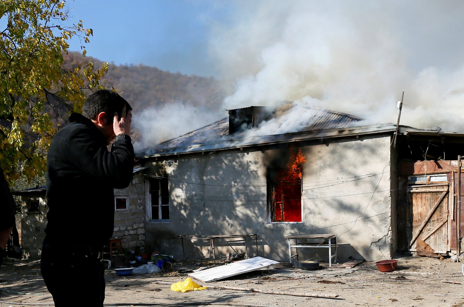 A man reacts as he stands near a house set on fire by departing ethnic Armenians, in an area that had been held under Armenian military control, in the village of Cherektar in the region of Nagorno-Karabakh, Azerbaijan, Nov. 14, 2020. (Reuters Photo)