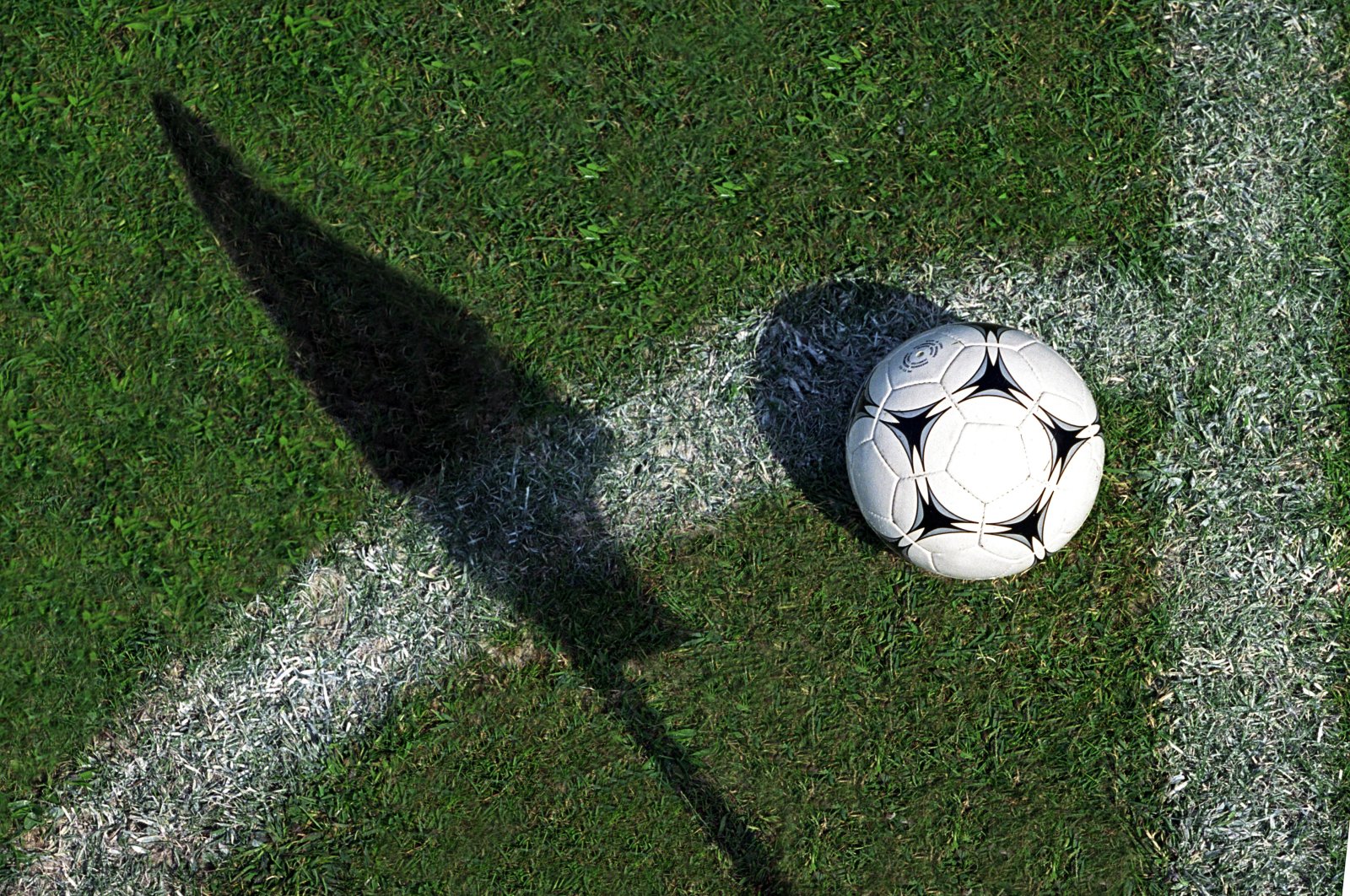 A football is seen as the corner flag casts a shadow on the pitch. (Getty Images) 