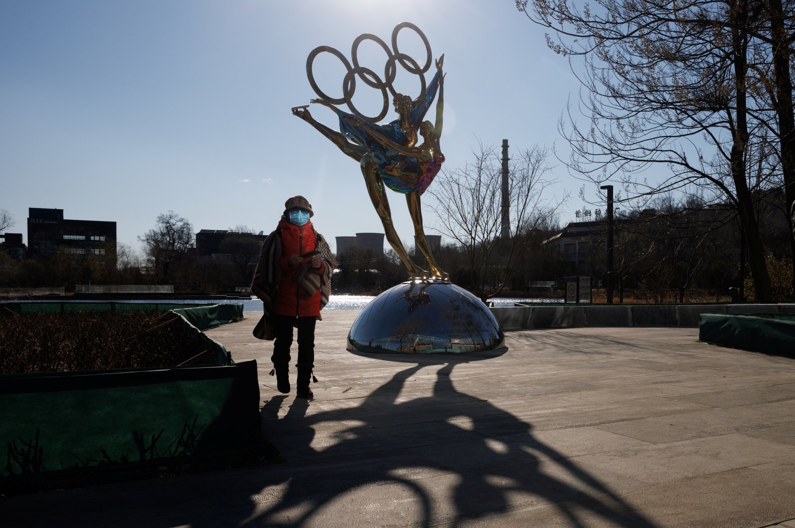 A woman walks past a statue featuring the Olympic Rings, Beijing, China, Nov. 30, 2021. (Reuters Photo)