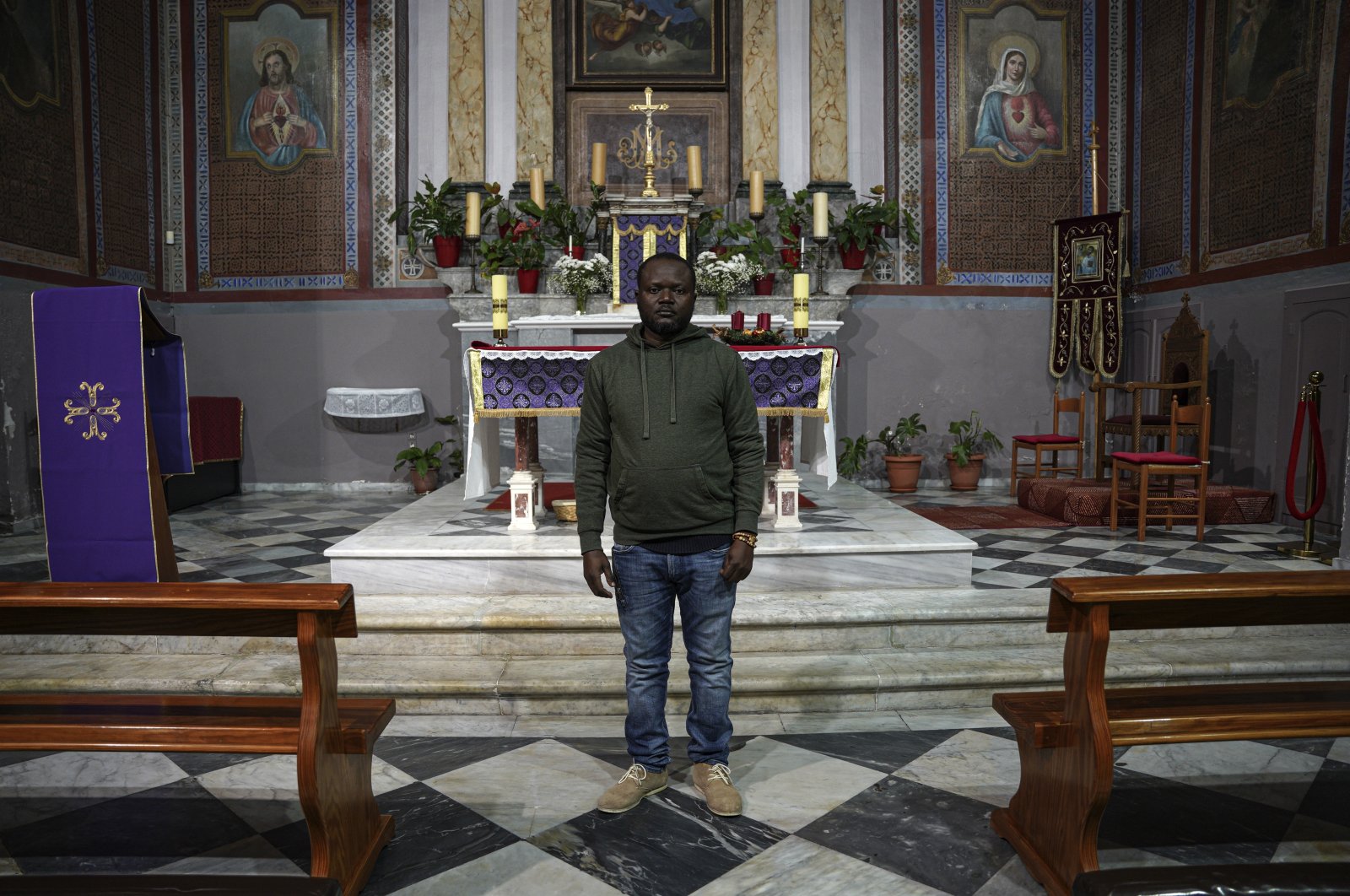 Christian Tango Muyaka, a 30-year-old asylum-seeker from Congo, poses for a photograph inside a Catholic church in Mytilene port, on the northeastern Aegean island of Lesbos, Greece, Monday, Nov. 29, 2021. Muyaka will attend a Sunday service held by the pope at a new migrant camp on Lesbos. (AP Photo)