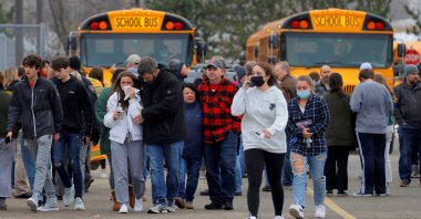Parents walk away with their kids from the Meijer's parking lot where many students gathered following an active shooter situation at Oxford High School in Oxford, Michigan, U.S. Nov. 30, 2021.  (Eric Seals-USA TODAY NETWORK via Reuters)