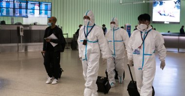 Air China flight crew members in hazmat suits walk through the arrivals area at Los Angeles International Airport in Los Angeles, California, U.S., Nov. 30, 2021. (AP Photo)