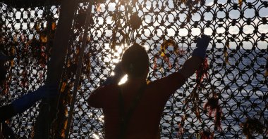 A fisherman holds the net aboard the trawler Le Chant des Sirenes (The Mermaids' song), fishing at the limits of the French-U.K. waters, off Granville, Normandy, Nov. 9, 2021. (AP Photo)