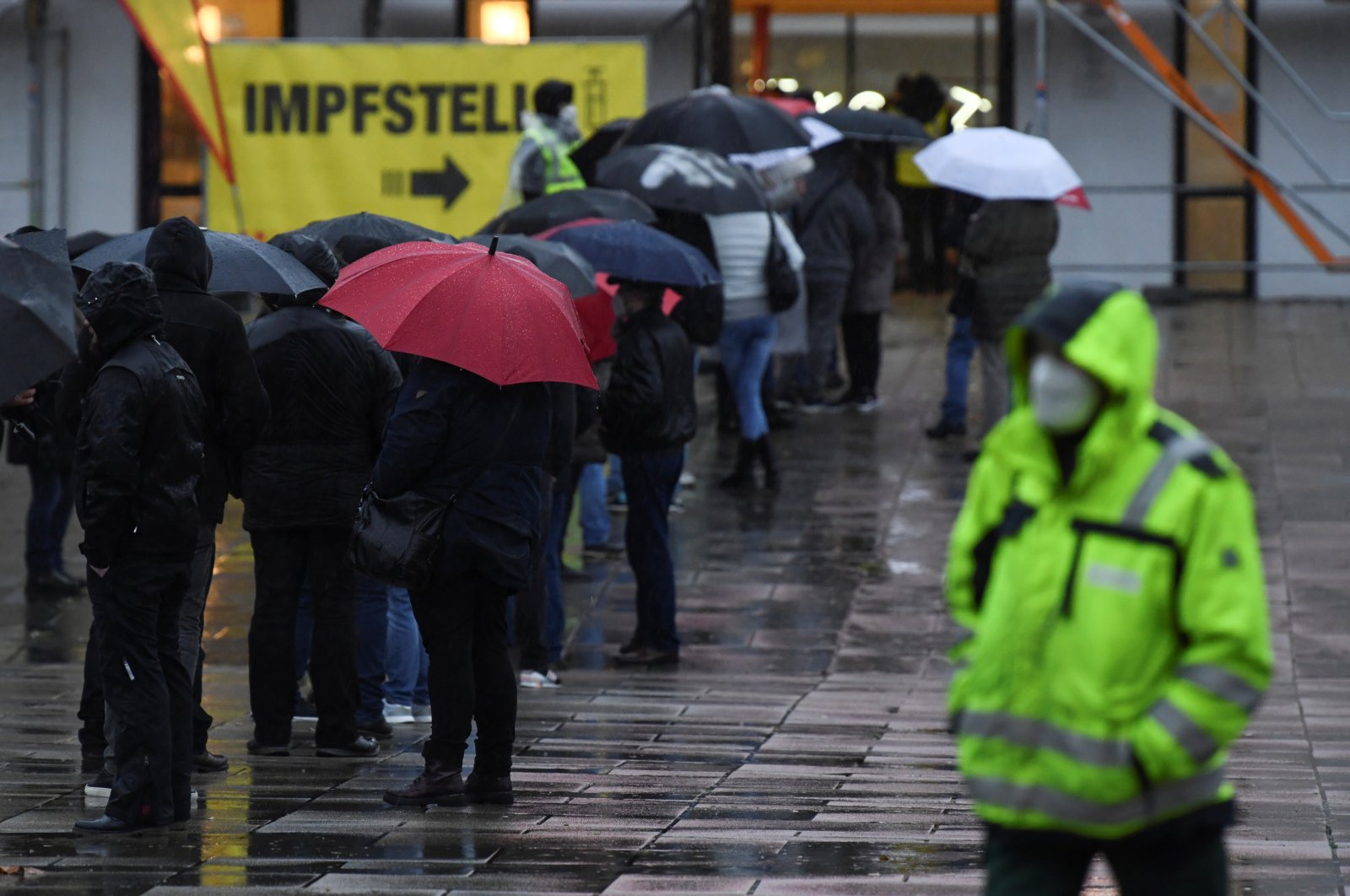 People hold umbrellas as they queue outside a vaccination center amid the COVID-19 pandemic during rainfall in the district of Marzahn-Hellersdorf, Berlin, Germany, Dec. 1, 2021. (Reuters Photo)